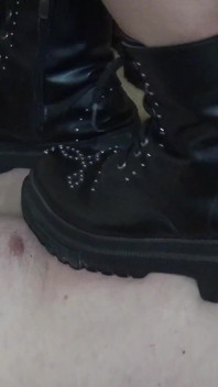 Calpestare con gli stivali sul corpo nudo