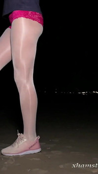 Anna de meia-calça branca e brilhante na praia noturna