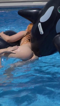 Meninas lésbicas estão se divertindo em uma piscina com um tubarão inflável