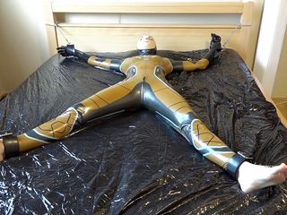 Latex Danielle: Latex Danielle is attached to the bed and masturbated with...