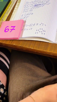 Studente 67 Six-Seven - hem plagen onder het bureau tijdens wiskunde. Klaarkomen op polshorloge