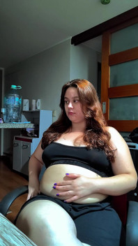 Sexy baculatá žena si plní své kulaté břicho sladkostmi