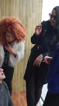 Fur-clad Femdoms Dominate Submissive on Balcony