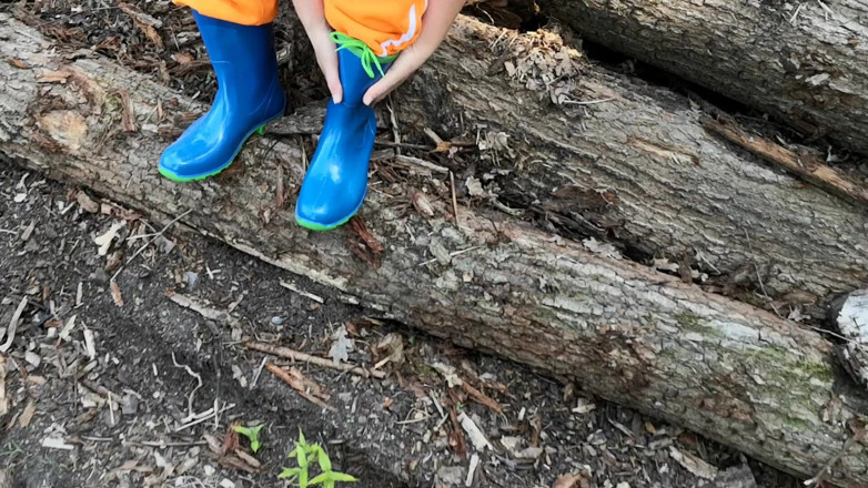 Bouncy Tits Action: Sitting in rubberboots on woodpile