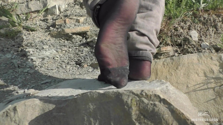 Mistress Legs: Jeans feet in black nylon socks on the seashore