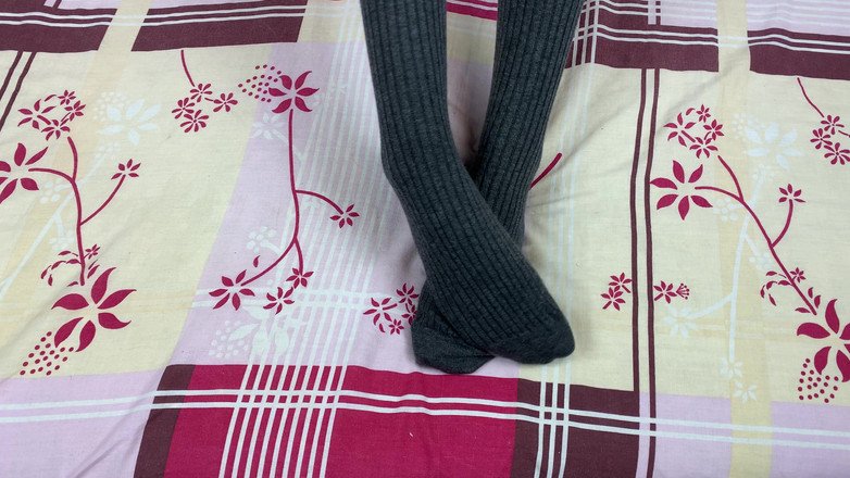 Gloria Gimson: Dziewczyna w szarych długich skarpetkach na nogach pieści się w łóżku