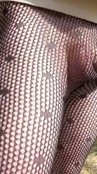 Walking in a park in fishnet tights.