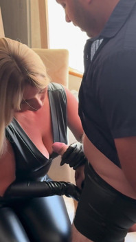 Secretară sexy într-o ținută de latex masturbându-și pula șefului ei în timp ce fumează