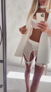 Monika Fox in White Posing in Front of a Mirror Before Shooting
